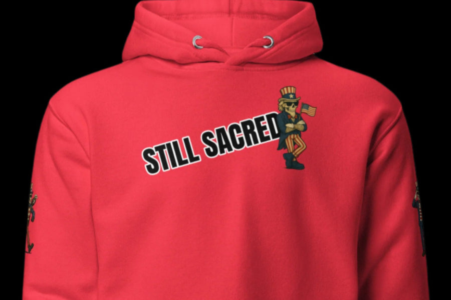 Still Sacred 4th of july team red hoodie, skelly holding flag. front view